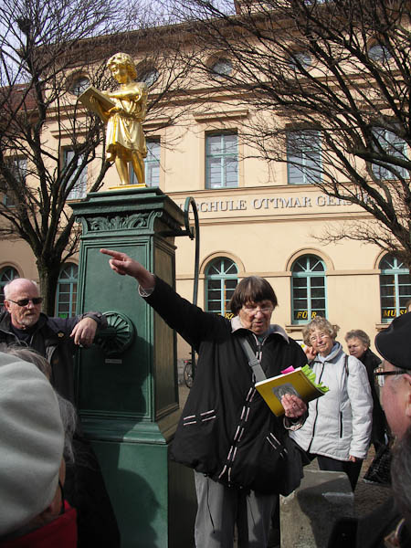 Gudrun Harnisch weist auf die Richtung unserer Wandergruppe hin - als Leiterin dieses Unternehmens der LEW hier am Lesem?nnchenbrunnen in Zentrum unserer Stadt